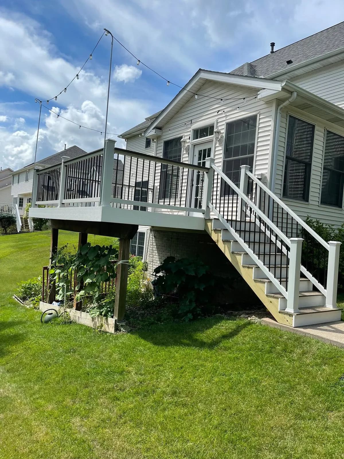 After: the rebuilt deck and stair from the yard, white rail against the house
